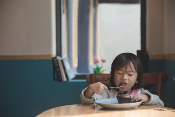 Asian little girl eating cake 