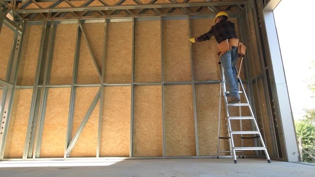 Caucasian Construction Worker on a Ladder. Steel Frame House Building