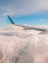 Fototapeta premium Aerial view of a plane's wing, blue sky and cotton clouds
