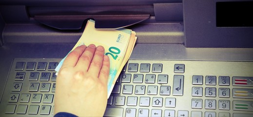 money at an ATM and the hand of a boy