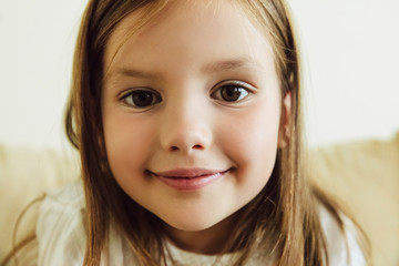 Close-up of cute little girl looking at camera and smiling. People. Smiles