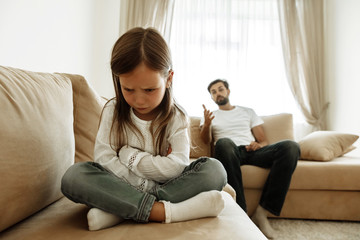 Childhood. Education. Problem. Offended little girl is crying, her father is talking to her in the background