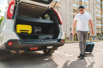 man putting bags in car trunk. ready for car travel