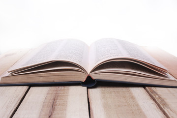 Opened Book on Wooden Table Against White Background