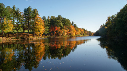 Fototapeta na wymiar Beautiful scene of the autumn colorful trees reflected in the water of a river during fall season in Massachusetts