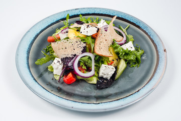 Fresh vegetable salad with cheese and slice of bread on blue plate