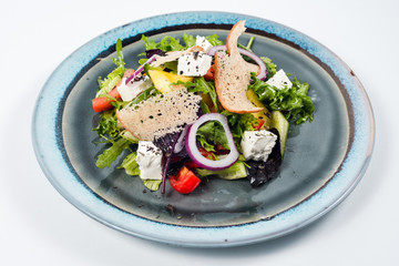 Fresh vegetable salad with cheese and slice of bread on blue plate