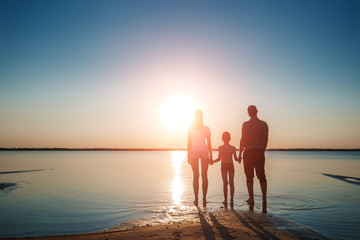 Family on the lake against a beautiful sunset. A happy life, happiness, family vacations.