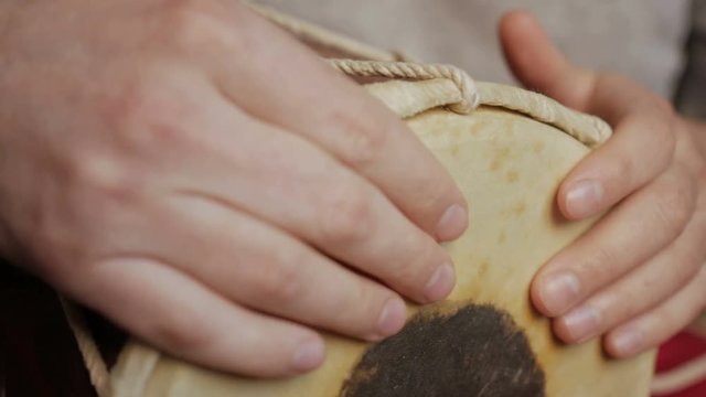 Close up of hands of a man playing a drum.