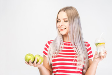 Portrait of young beautiful woman holding in hands glass of water and fresh green apple isolated over white.