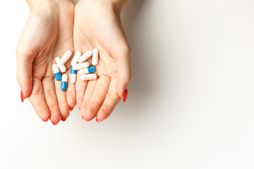 Colorful pills and tablets in the woman hands on white background. Top view. Flat lay. Copy space. Medicine and health care concept