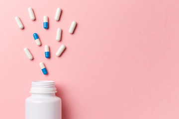 Assorted pharmaceutical medicine pills, tablets and capsules and bottle on pink background. Top view. Flat lay. Copy space. Close up. Medicine concept. Heap of pills on pink background