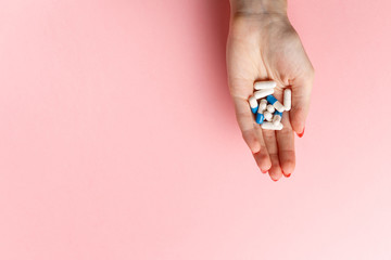 Colorful pills and tablets in the woman hand on pink background. Top view. Flat lay. Copy space. Medicine concept