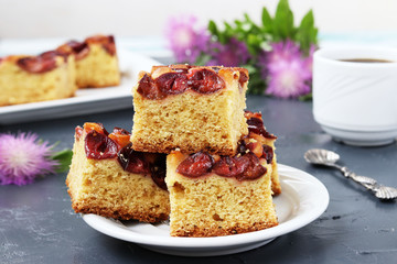 Slices of a plum pie on a plate, are located on a dark background