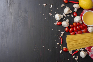 Spaghetti ingredients on black wooden desk, top view.
