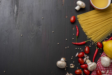 Spaghetti ingredients on black wooden desk, top view.
