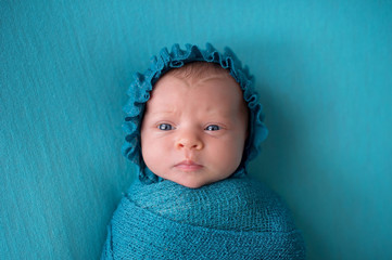 Perplexed Newborn Baby Girl Wearing a Turquoise Blue Bonnet