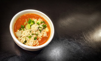 Chili Sauce Mixed with Minced Garlic, Green Onion and White Sesame in a dish on a Dark Background.
