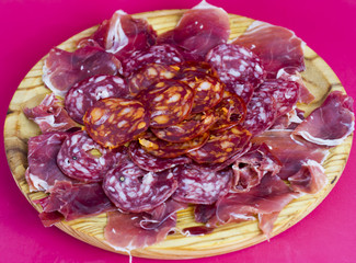 Typical spanish food with ham and sausage on a wooden plate