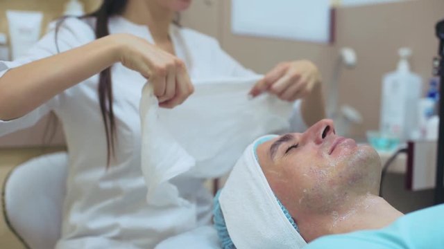 Men`s cosmetology. Young male receiving facial procedures at beauty clinic. Skin cleaning 