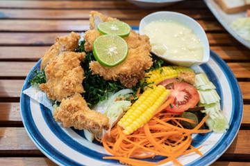fried chicken ,salad vegetable, lemon  with Caesar Salad Dressing . selective focus ,topview . clean and healthy food concept.