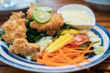 fried chicken ,salad vegetable, lemon  with Caesar Salad Dressing . selective focus ,topview . clean and healthy food concept.
