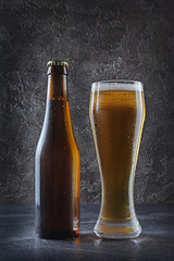 Bottle of cold beer and glass with foam