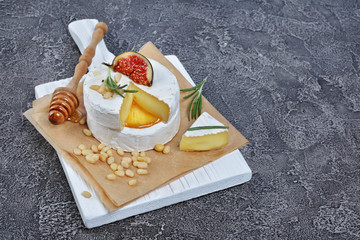 Gourmet appetizer of white brie cheese or camembert with fresh figs, pine nuts, honey and rosemary...