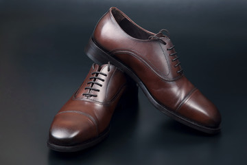 Classic men's brown Oxford shoes on dark background