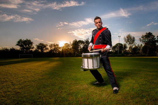 Cool portrait of musician in uniform with atmospheric light on a green grass field at sunset