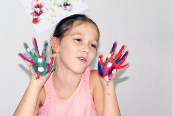 little girl draws with paints, the child has stained all hands in different colors