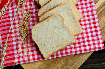 White bread toast with Wheat and red tablecloth on wooden background.