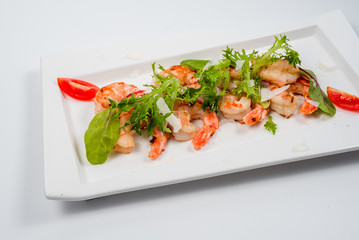 salad of fried shrimp with herbs and tomatoes on a white plate