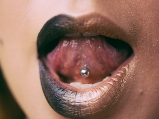 Close-up of lips and piercings in the tongue. Fashionable concept.