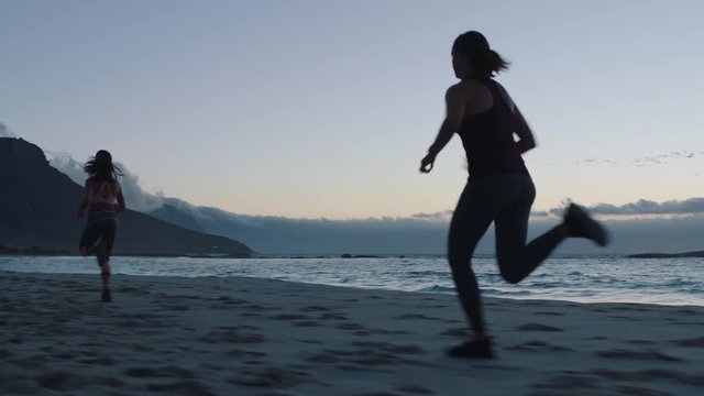 competitive young woman athlete running overtaking in race competition female runners training intense cardio workout on beach at sunset