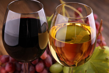 White wine and red wine in a glass with fall grapes on rustic background.