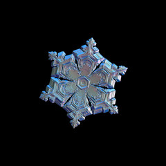 Snowflake isolated on black background. Macro photo of real snow crystal: elegant star plate with fine hexagonal symmetry, six short, broad arms and glossy, relief surface with complex inner pattern.