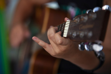 Young musician play chord on guitar.