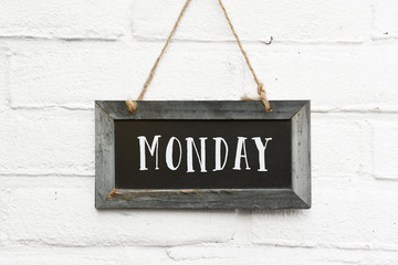 Hello monday text on hanging board white brick outdoor wall
