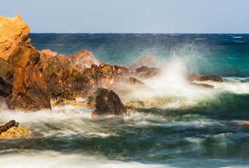 Turquise sea water sprayed on golden cliff.