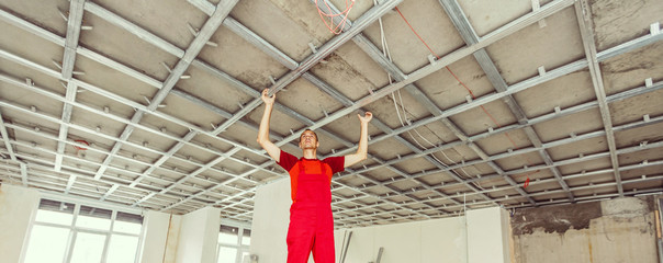 Man in builder uniform installing suspended ceiling