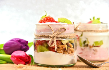 Mixed fruits and walnuts yogurt in glass with bow tie on Bokeh background..Breakfast with many kind of fruits and yogurt.