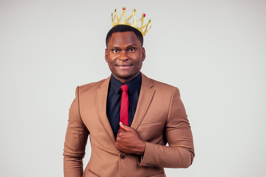 smart african american successful and rich businessman in a stylish suit and the golden crown on his head on white background in studio shot. the concept of well-deserved respect and luck