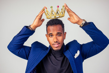 smart african american successful and rich businessman in a stylish suit and the golden crown on...