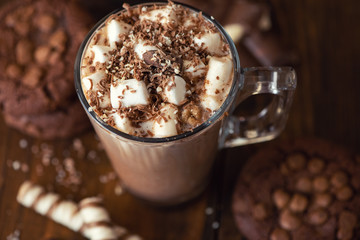 Cup of cocoa with marshmallows and chocolate chip cookies on dark wooden background. Close Up