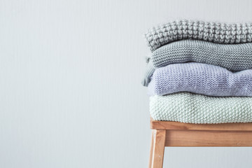 Stack of cozy knitted clothes on a wooden ladder. Vintage tinting