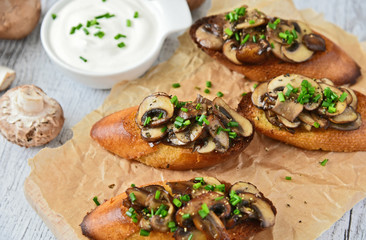 Champignon or brown cap mushroom Crostini on brown paper and wooden board.