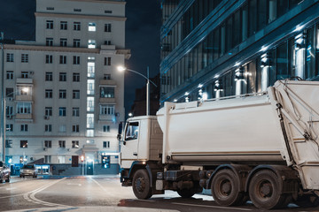 White truck at night city next to modern buildings.