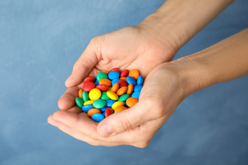 Woman holding glazed candies on color background, closeup