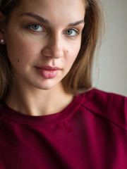 Fashion photo of a beautiful smiling brunette woman in a red sweater posing over gray empty background.